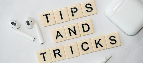 Brickor med bokstäver där det står tips och tricks som ligger på ett skrivbord med en penna och airpods
